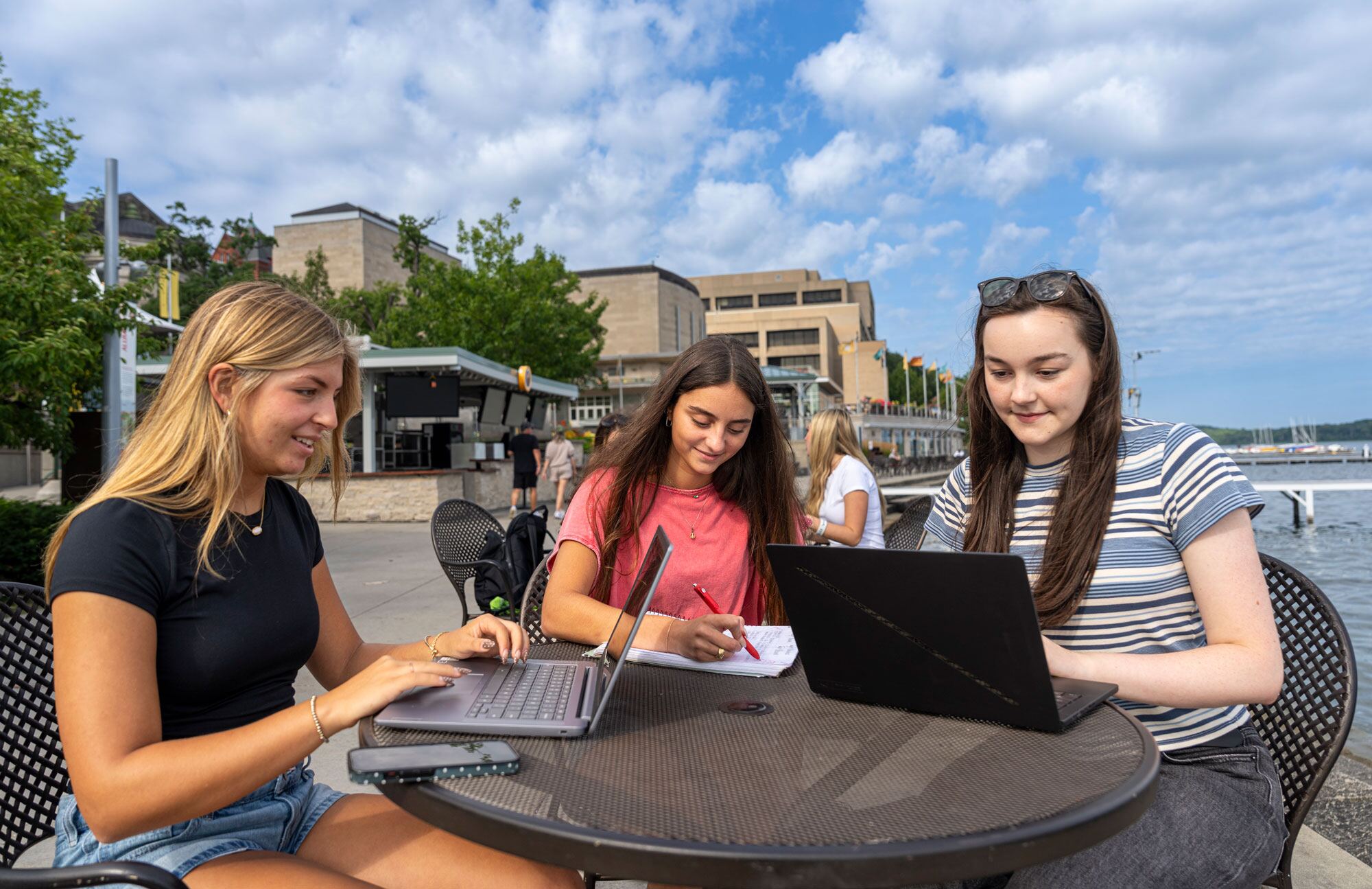 Three students doing coursework on the Union Terrace on a beautiful summer day