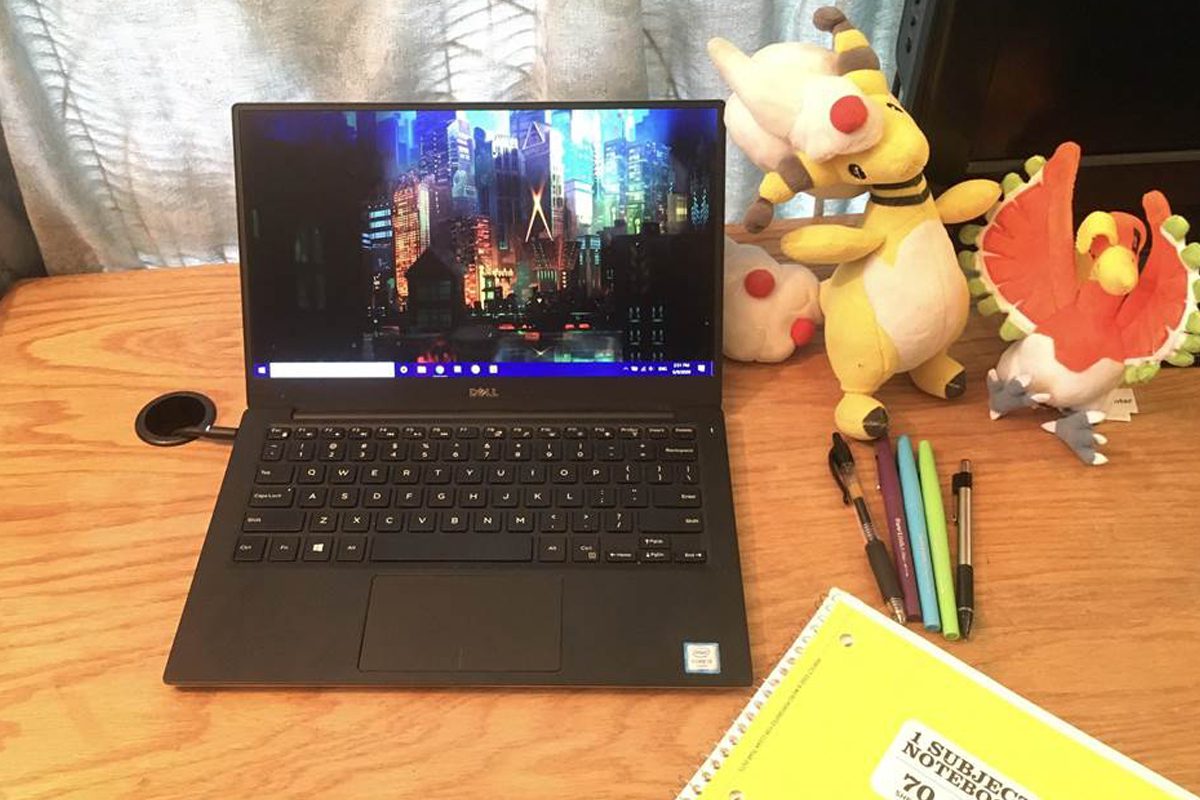Open laptop on desk with nighttime cityscape screen saver, plush Pokemon toys next to laptop