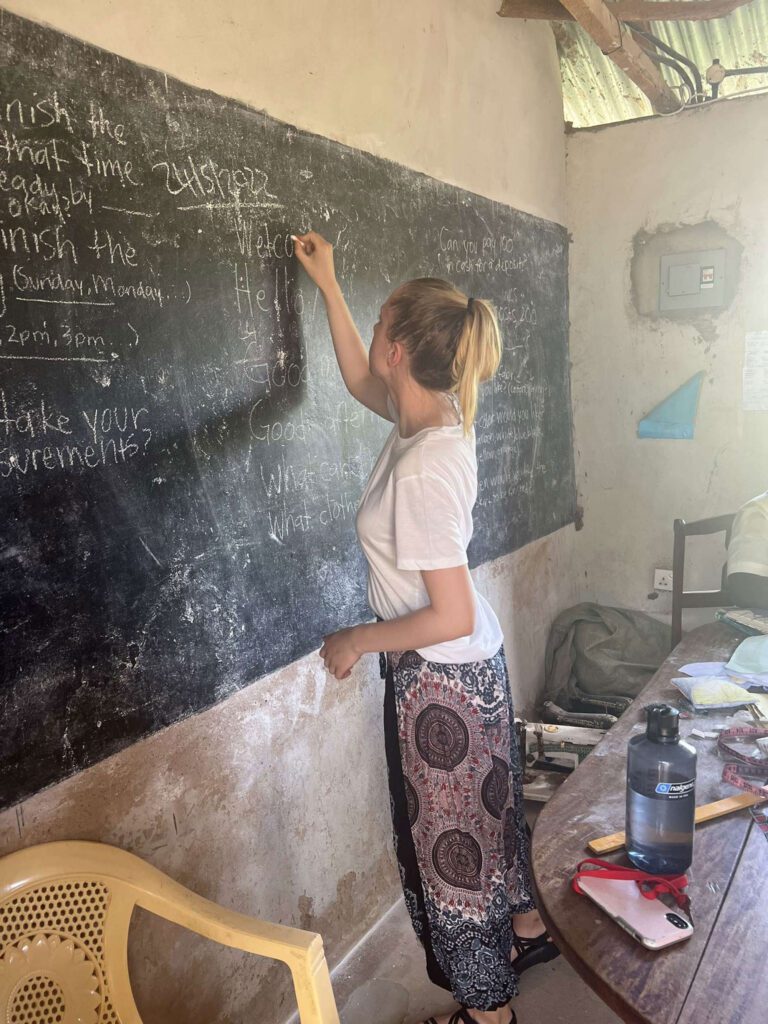 Student wearing a skirt and writing on the blackboard in class.