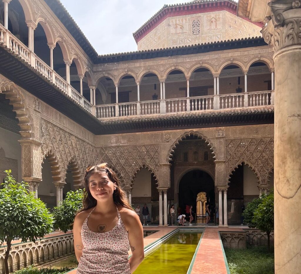 Un estudiante se para en un patio en Sevilla, España, sonriendo
