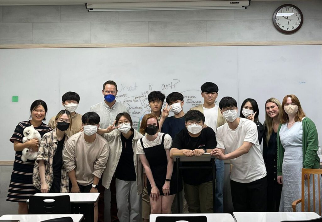 Students wearing masks, standing for a group photo in a classroom