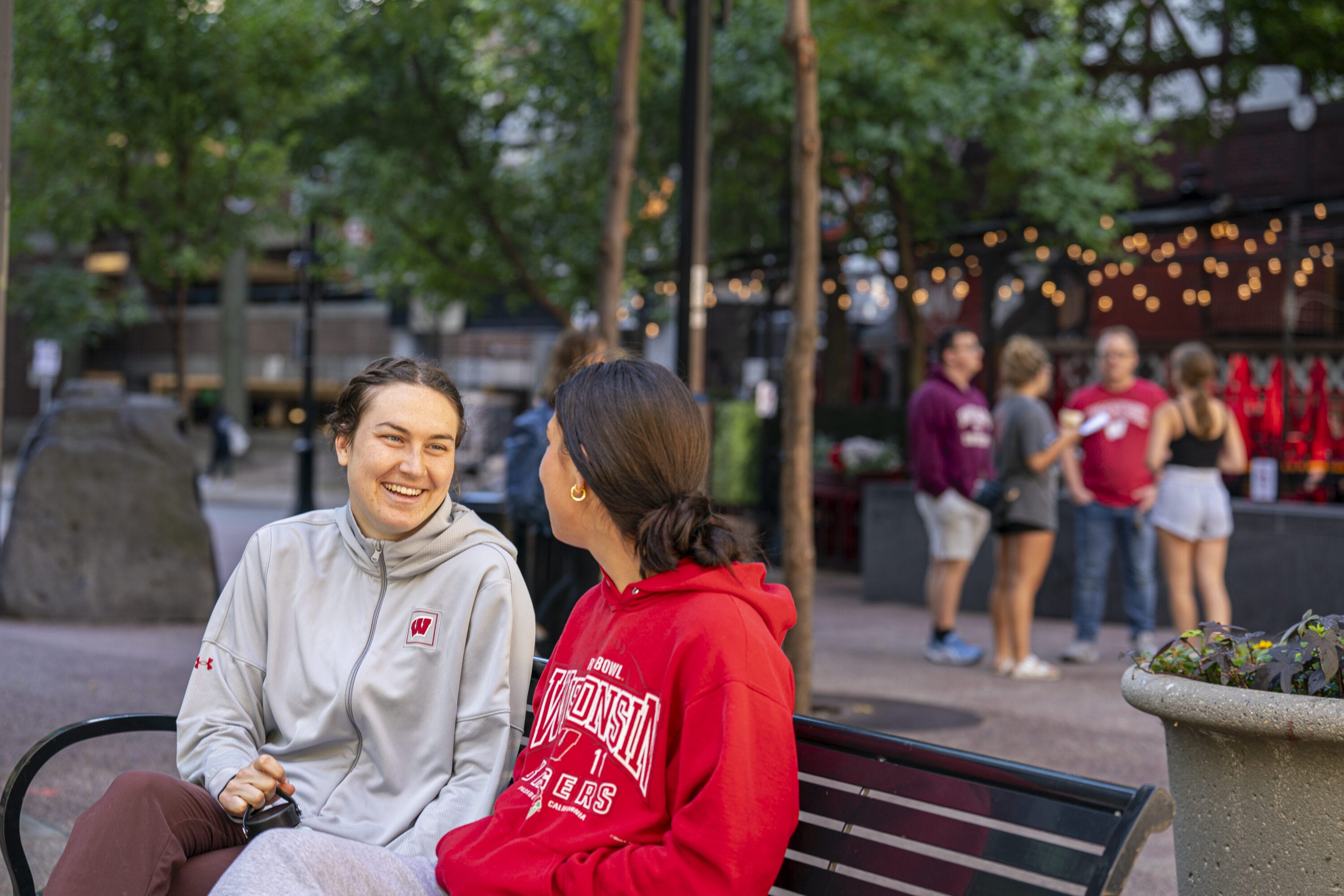 Two UW-Madison students sitting on a bench speaking.