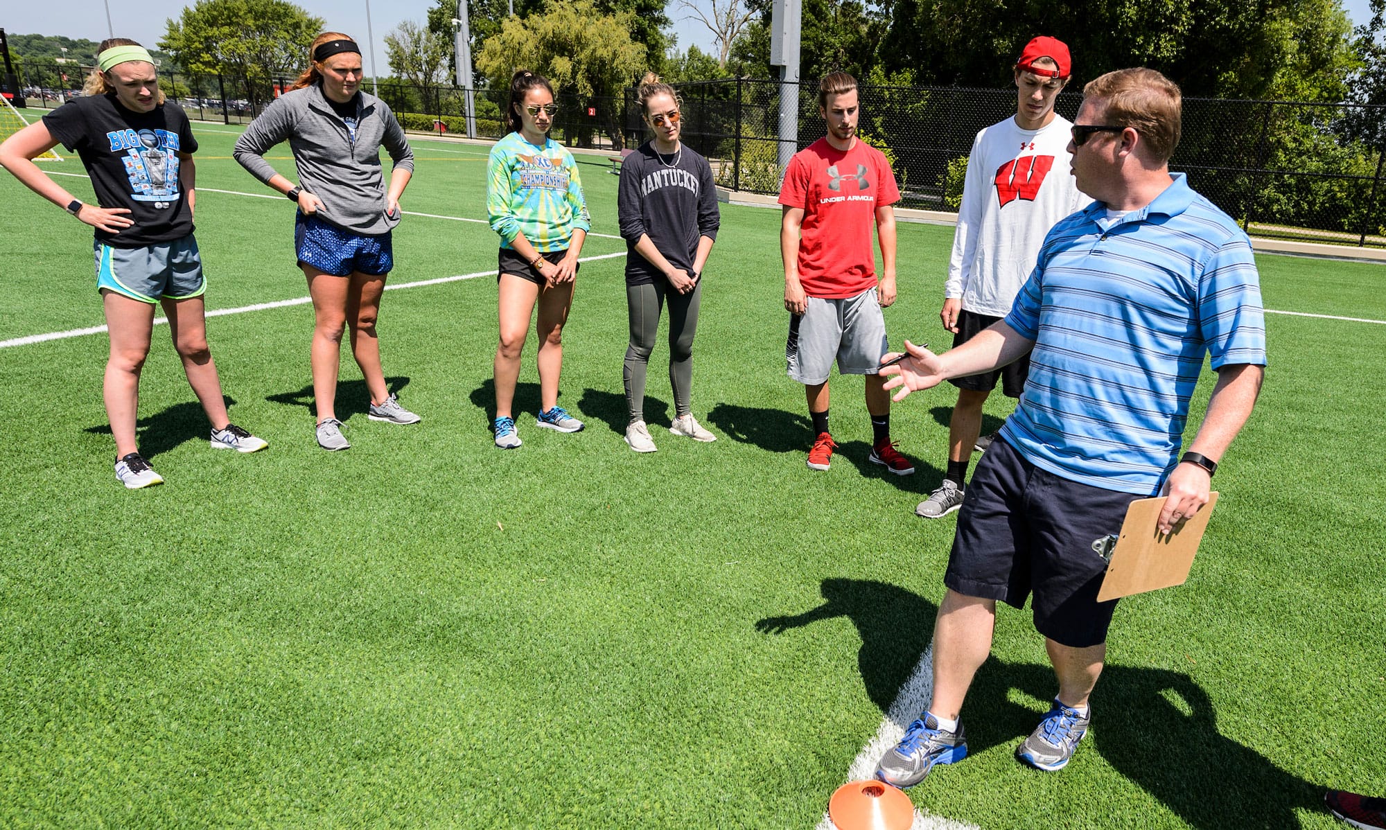 A coach teaching a group of students how to kick a ball.