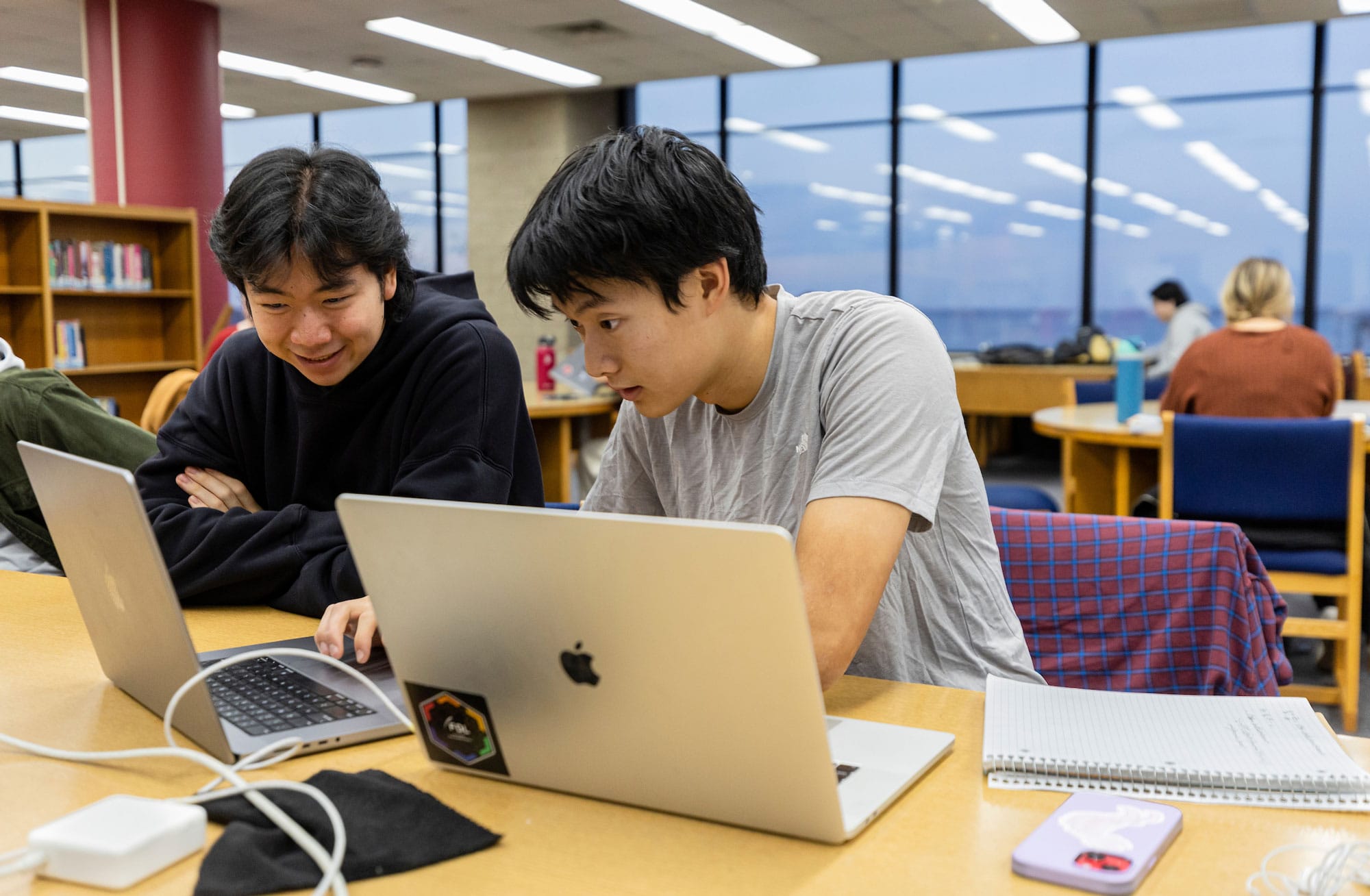 Two students working on a project on their laptops.