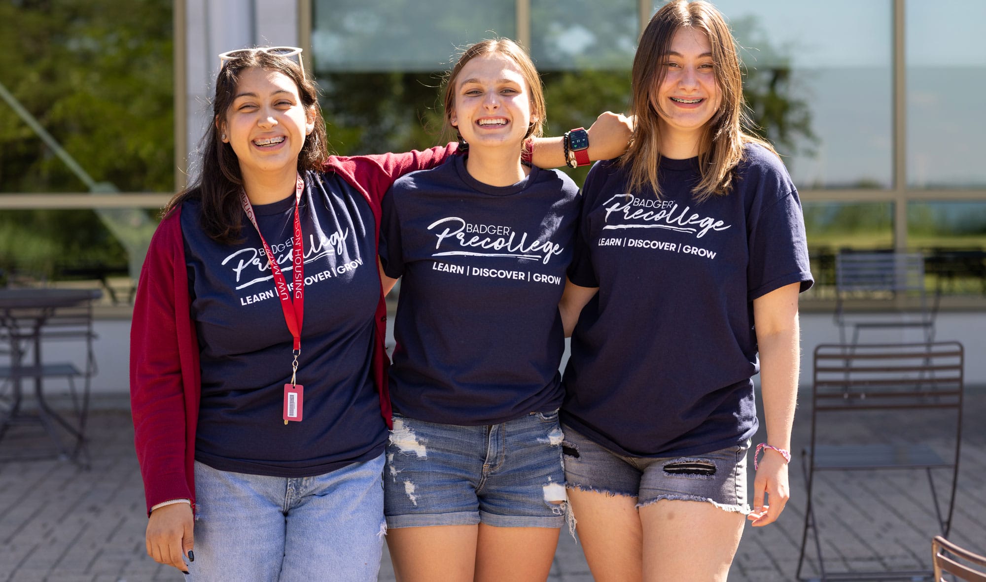 A trio of students wearing UW-Madison gear posing for a group photo.