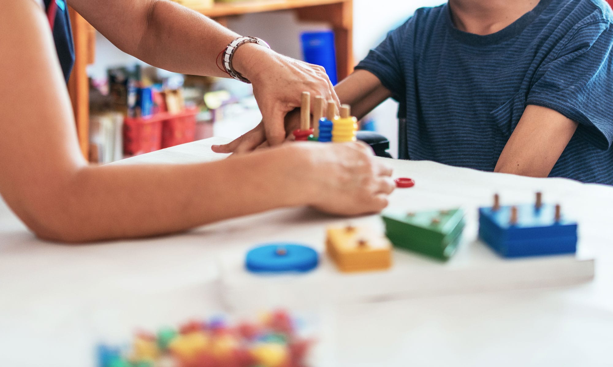 Closeup of the hands of a teacher and special ed student working with educational toys