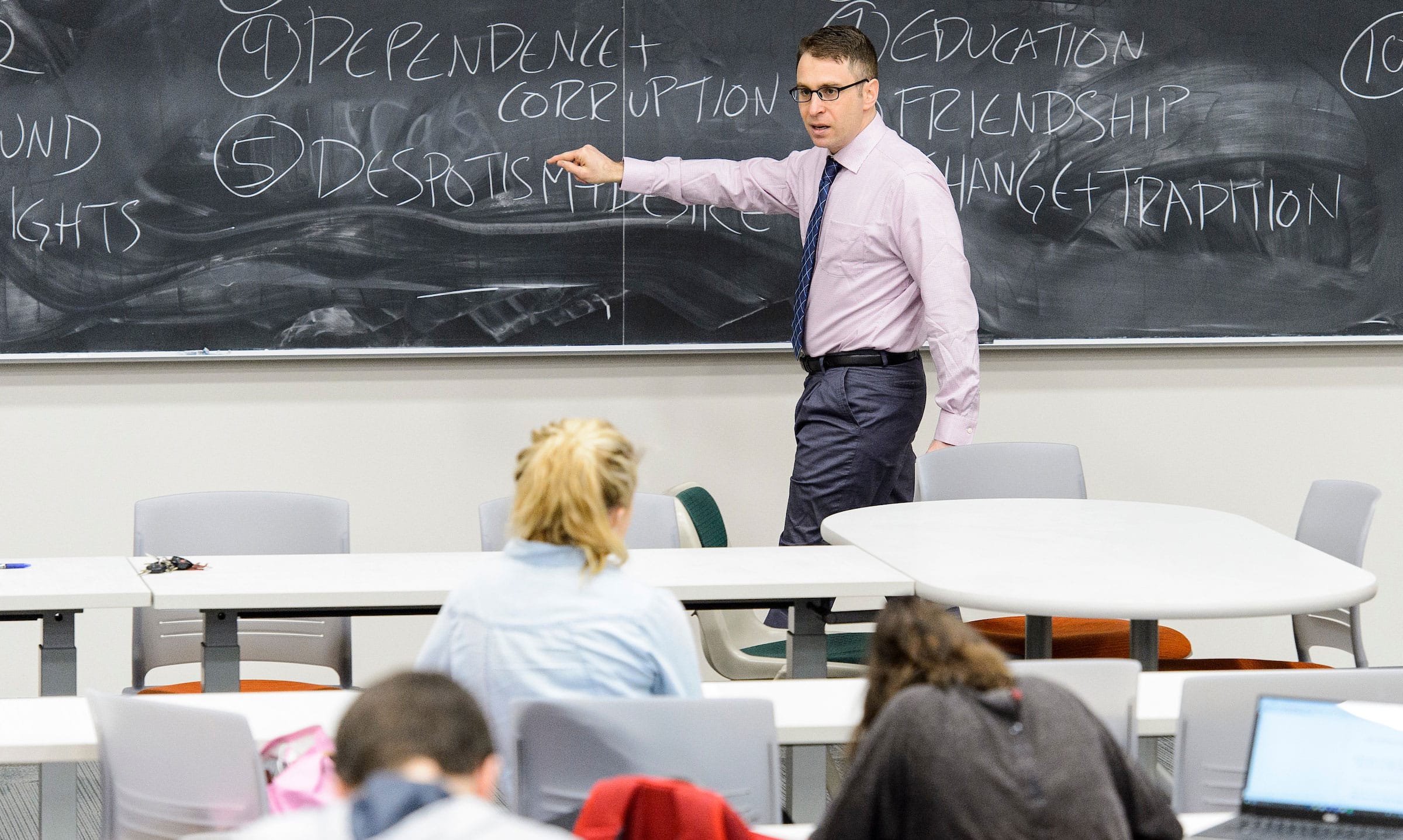 Professor Daniel Kapust writing on chalkboard while teaching a class