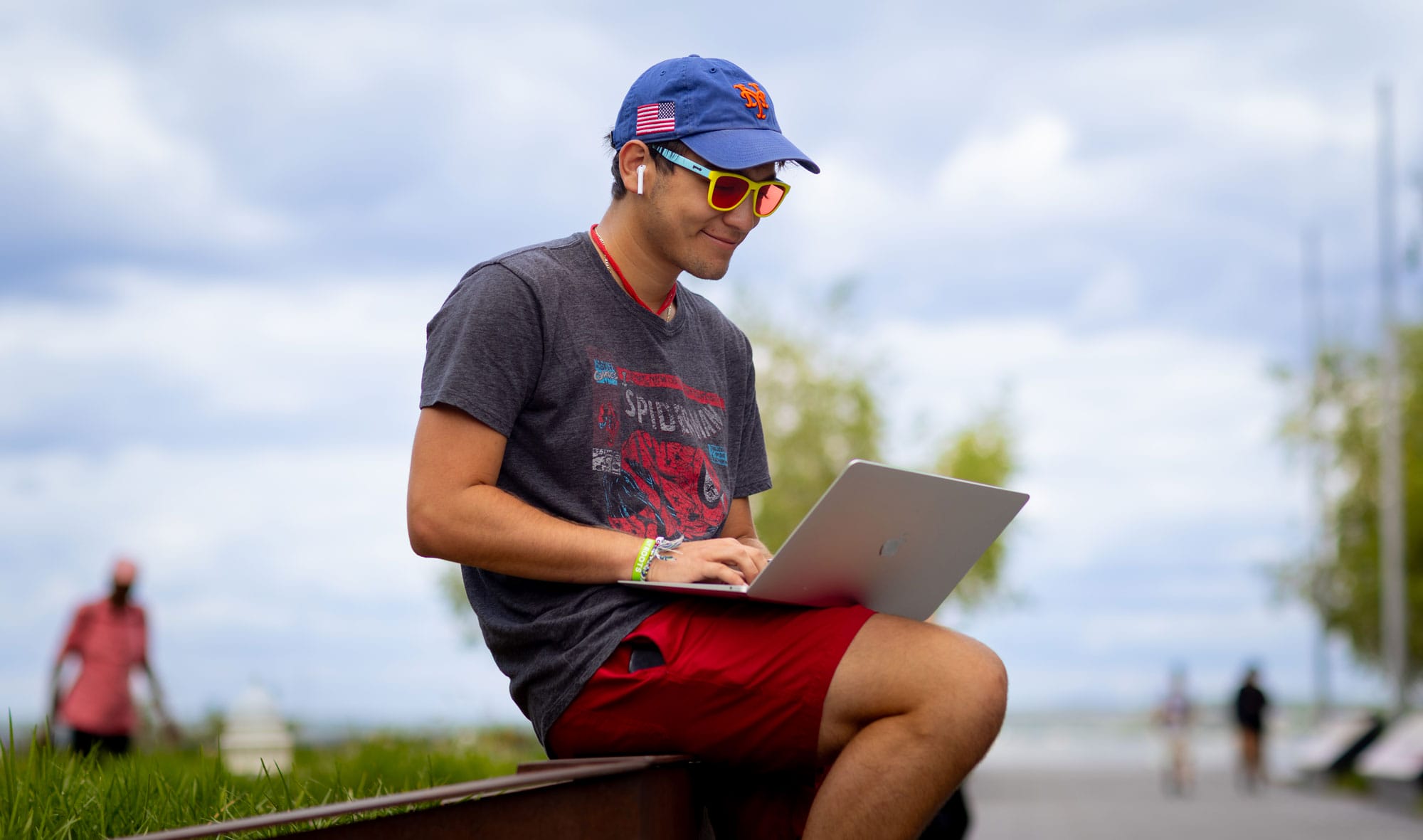 A student sitting outside, working on his laptop.