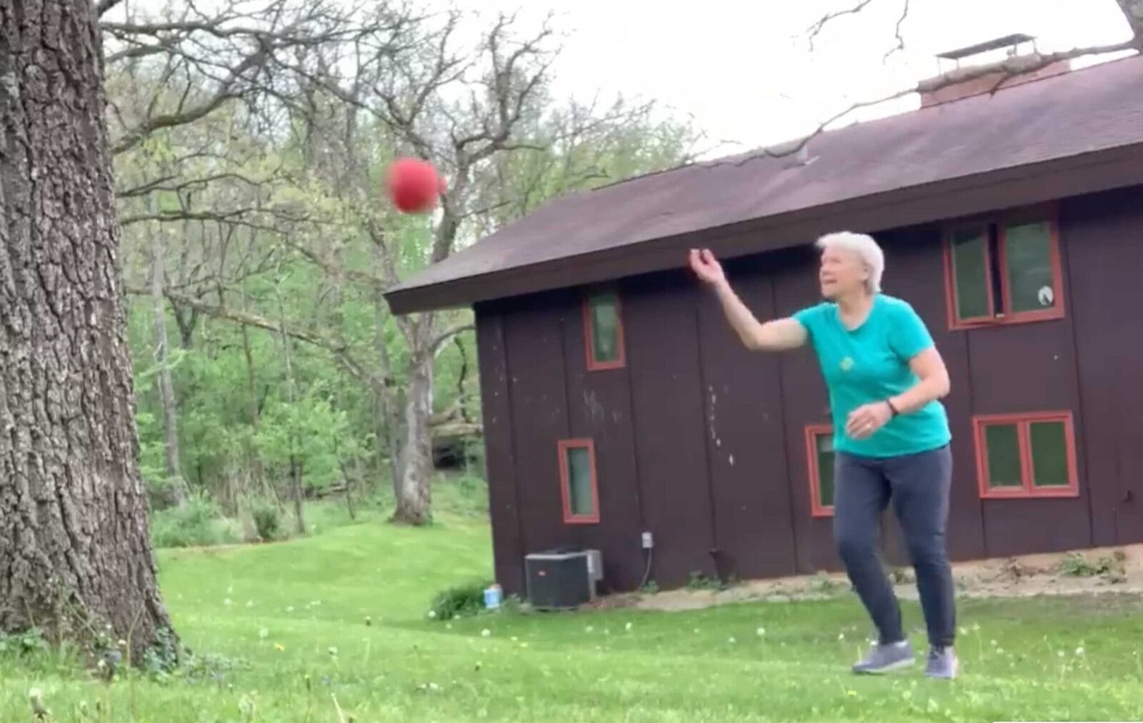 Cindy Kuhrasch tosses a red ball against a tree outside