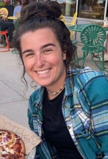 UW student Sara Kaska sitting outside on the Memorial Union Terrance eating pizza