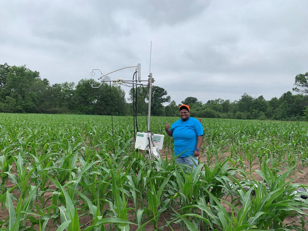 Student Sharifa Brevert standing in a field, doing research for a class