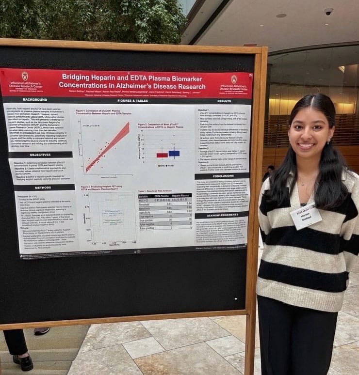 Mariam Siddiqui stands next to a research poster posted on a movable chalkboard