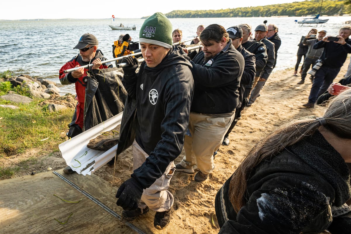 Members of the recovery dive team, along with tribal members of the Ho-Chunk Nation, transport a 3,000-year-old dugout canoe from Lake Mendota